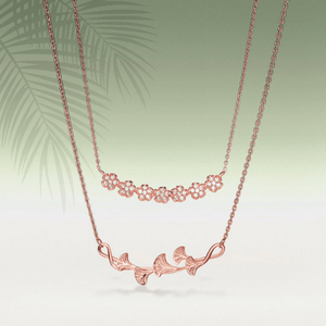 Rose gold necklace with floral design on a light green background