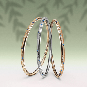 Three bangles in gold, silver, and rose gold on a light green background