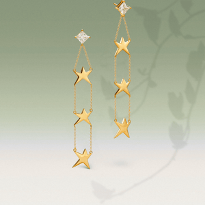 Gold star earrings on a gradient background