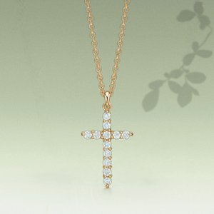 Gold cross necklace with diamonds on a light green background