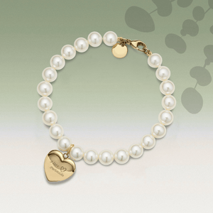 Pearl bracelet with a gold heart-shaped tag on a light green background