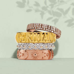Stack of gold, rose gold, and silver rings on a light green background
