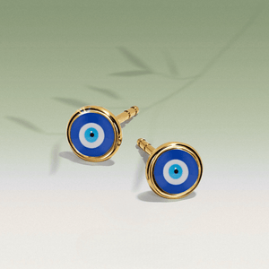 Pair of blue evil eye earrings with gold accents on a light green background