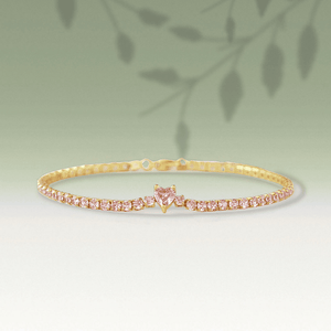 Gold bracelet with pink gemstones on a light green background