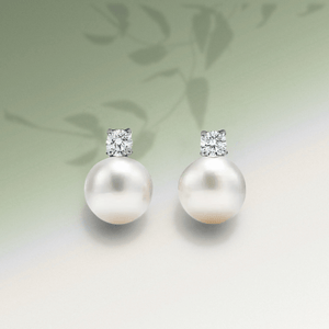 Pearl earrings with diamond-like tops on a light background