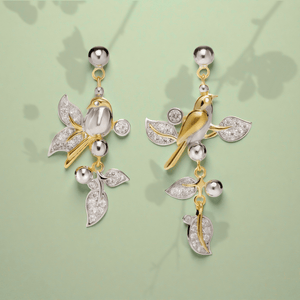 Pair of gold and silver bird-shaped earrings on a light green background