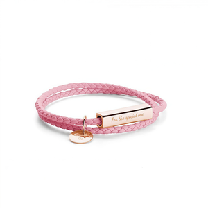 Pink braided leather bracelet with a gold tag on a white background