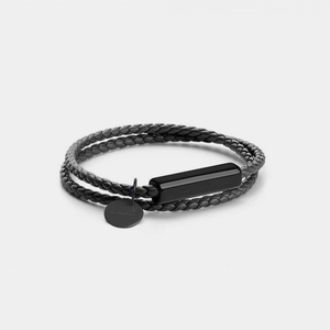 Black braided bracelet with a bar and round charm on a light gray background