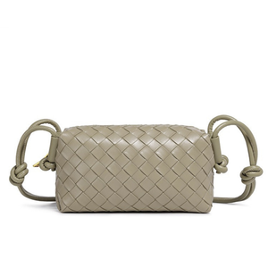 Sage woven handbag with knotted handles on a white background