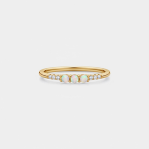 Gold ring with opal stones and diamonds on a light gray background