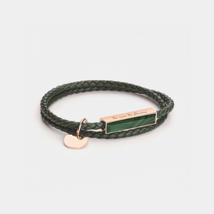 Green braided bracelet with a rectangular tag and heart charm on a light gray background
