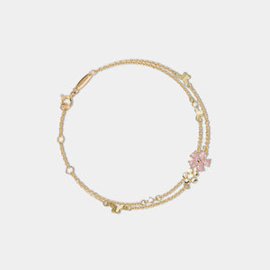Gold bracelet with a pink flower charm on a white background