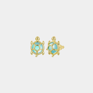 Gold sea turtle-shaped earrings with blue cubic zirconia centers on a light gray background