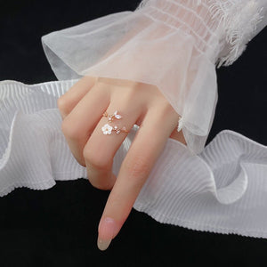 Hand wearing a delicate floral ring with white lace fabric in the background