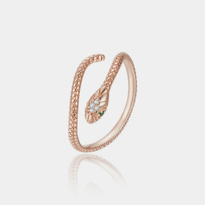 Rose gold snake-shaped ring with green gemstones on a light gray background