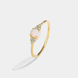 Gold ring with a pink gemstone on a light gray background