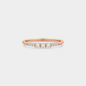 Rose gold ring with opal stones and small diamonds on a light gray background