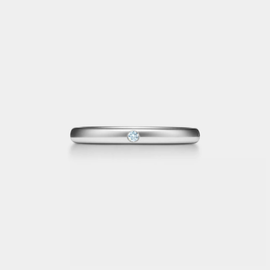 Silver ring with a small moissanite on a light gray background