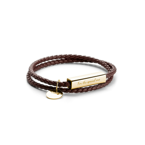 Brown braided leather bracelet with gold tag and heart charm on a white background