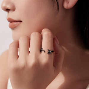 Close-up of a hand wearing a delicate black wrap ring with cat design.