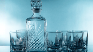 Set of crystal glasses with a decanter on a light blue background