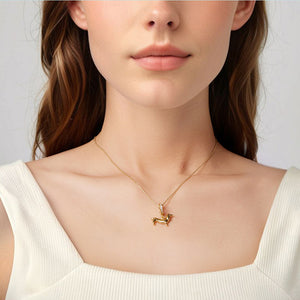 Gold necklace with a dachshund dog pendant worn by a person against a neutral background
