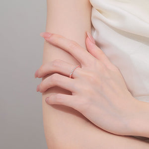 Close-up of a hand wearing a moissanite ring on a neutral background