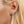 Close-up of an ear wearing a starfish-shaped turquoise earring with blonde hair.