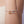 A bracelet with two dachshund charms on a wrist against a neutral background