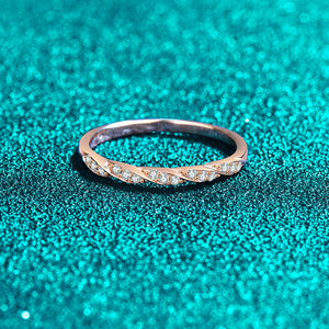 Rose gold ring with small moissanite on a teal glittery background