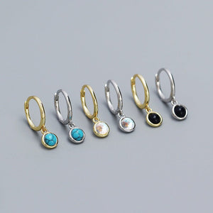 Set of hoop earrings with various gemstone drops on a gray background