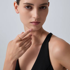 Woman wearing a gold ring on a plain background