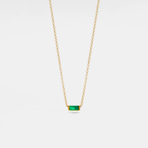 Gold necklace with a green gemstone on a white background