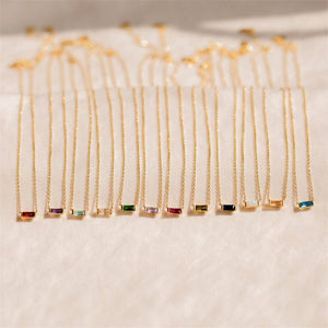 Gold necklaces with colorful gemstones on a light background