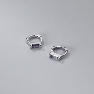 Silver hoop earrings with purple gemstones on a gray background