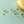Gold hoop earrings with green gemstones on a light green background
