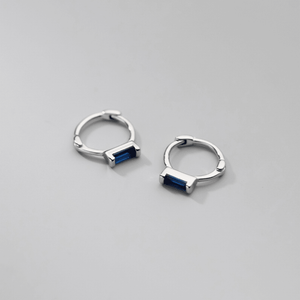 Silver hoop earrings with blue stones on a gray background