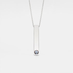 A gold-plated necklace with a vertical rectangular charm featuring a small crystal or pearl on the bottom side, attached to a chain.
