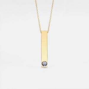 Gold necklace with a vertical bar pendant on a light gray background