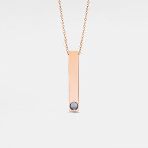 A gold-plated necklace with a vertical rectangular charm featuring a small crystal or pearl on the bottom side, attached to a chain.