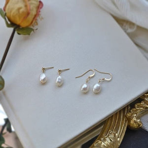 Pearl earrings on a white surface with a decorative gold frame.