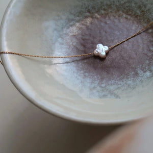 Necklace with a cloud-shaped pendant on a ceramic surface
