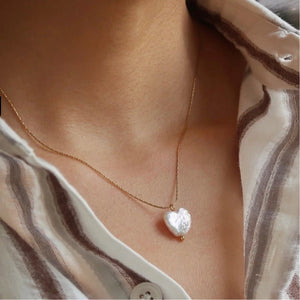 Heart-shaped pearl necklace on a person wearing a striped shirt
