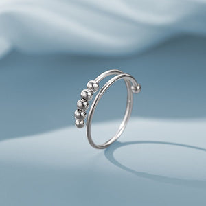 Silver ring with small beads on a light blue background