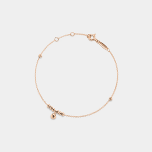 A delicate gold-colored anklet with bell-shaped pendants on a white background.
