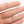 Gold '1985' necklace on a hand against a white background