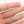 Gold necklace with '2012' pendant held between fingers on a white background