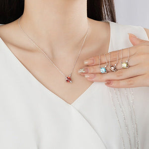 Necklace with a pendant on a model wearing a white top, with a hand holding three additional pendants.