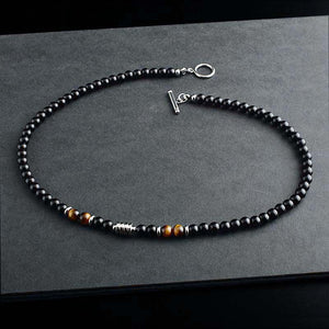 Three black agate crystal bead necklaces with varying details, displayed on a grey surface. One necklace features gold plating, another has a smooth finish, and the third includes metallic bead accents.