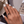 Hand with white nail polish wearing two rings, blurred background